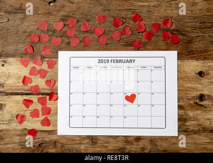 Konzeptionelle Bild von 2019 Februar Kalender und Gegenwart Geschenk mit roter Schleife auf rustikalen vintage Tabelle in sich bereit für Saint Valentines Tag gewickelt Stockfoto