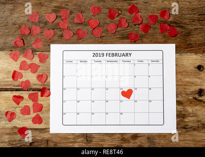 Konzeptionelle Bild von 2019 Februar Kalender und Gegenwart Geschenk mit roter Schleife auf rustikalen vintage Tabelle in sich bereit für Saint Valentines Tag gewickelt Stockfoto