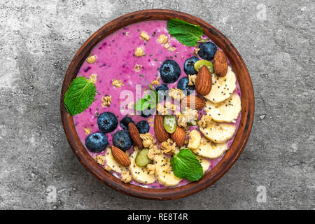 Acai smoothie Schüssel gefüllt mit Banane, Chia und Kürbiskerne, Blaubeere, Mandeln und Müsli. gesund vegan Frühstück. top View Stockfoto