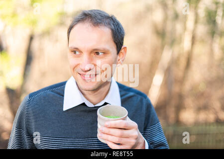 Glückliche Menschen Porträt holding Tasse Tee draußen auf Hinterhof deck Garten trinken Matcha Tee trinken im Frühjahr oder Herbst Stockfoto