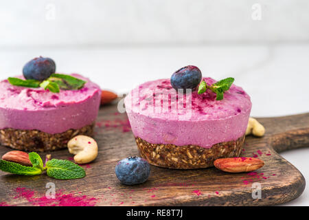 Raw vegan Heidelbeeren und Acai cashewkerne Kuchen auf einem Holzbrett. Ein gesunder Nachtisch. Nach oben Schließen Stockfoto