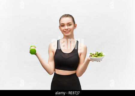 Sport, gesunder Lebensstil, Personen Konzept - Junge brünette Frau mit Salat und eine Hantel. Sie lächelt und geniessen die gesunde Lebensweise. Stockfoto