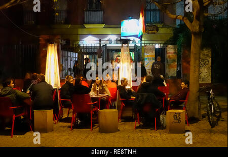 An einem kühlen Winterabend in einem Café in der Alameda de Hércules in Sevilla, Spanien, werden die Menschen an Tischen unter freiem Himmel sitzen Stockfoto