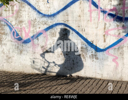 Schatten der Mann auf dem Fahrrad auf Stadt Beton Wand mit Graffiti Stockfoto