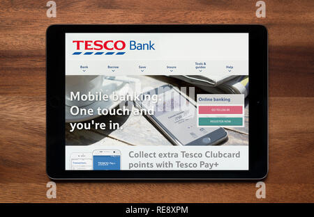 Die Website von Tesco Bank gesehen auf einem iPad Tablet, der ruht auf einem Holztisch (nur redaktionelle Nutzung). Stockfoto