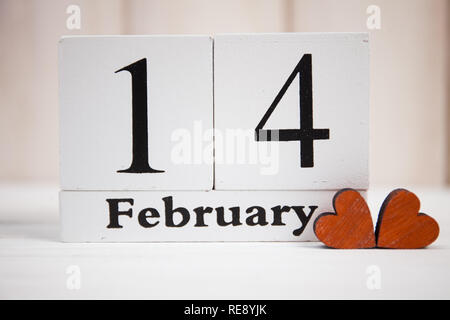 Valentines Tag Karte mit Holzblock Kalender auf weißem Hintergrund und Herzen aus Holz Stockfoto