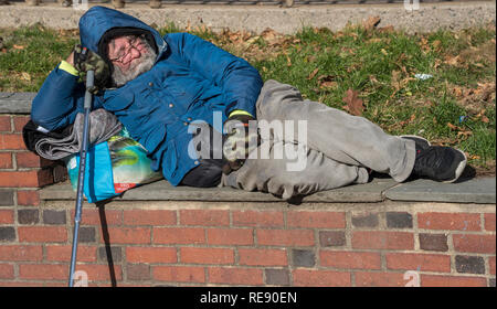 Boston, Massachusetts - Oktober 25, 2018 - Obdachlose Mann schläft auf einer Wand in einem Park Stockfoto