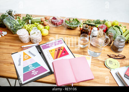 Ernährungswissenschaftler arbeiten mit Zeichnungen auf das Thema der gesunden Ernährung, leer Notebook und verschiedene Produkte auf den Tisch Stockfoto