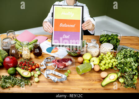 Ernährungsberater Förderung gesunden, ausgewogenen Essen an den Tisch voller variuos Produkte sitzen Stockfoto