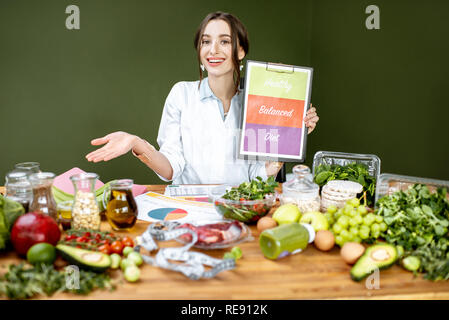 Ernährungsberater Förderung gesunden, ausgewogenen Essen an den Tisch voller variuos Produkte sitzen Stockfoto