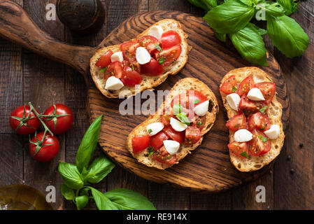 Klassische italienische Bruschetta mit Tomate Mozzarella auf Holz serviert. Tabelle Ansicht von oben. Antipasti, Vorspeise Stockfoto