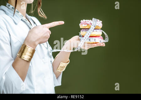 Frau, auf dem süssen Donuts auf dem grünen Hintergrund. Ungesunde Ernährung und Adipositas Konzept Stockfoto