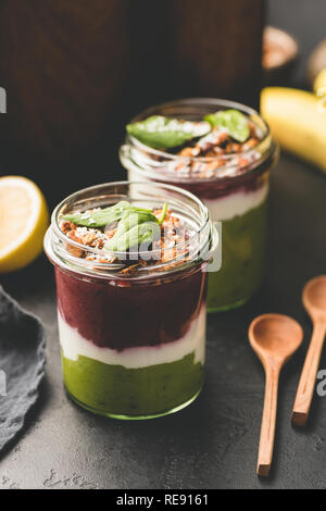 Layered acai avocado Smoothie in jar gekrönt mit Müsli und Spinat Blatt, gesundes Frühstück oder einen Snack. Veganes Essen, gesundes Essen Konzept Stockfoto