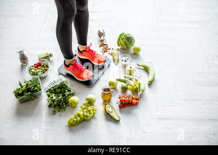 Sport Frau wiegen auf der Waage mit gesunden Lebensmitteln um. Gewichtsverlust, gesundes Essen und Sport Lifestyle Konzept Stockfoto