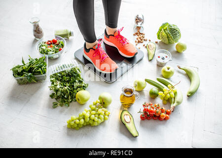 Sport Frau wiegen auf der Waage mit gesunden Lebensmitteln um. Gewichtsverlust, gesundes Essen und Sport Lifestyle Konzept Stockfoto