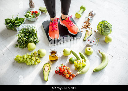 Sport Frau wiegen auf der Waage mit gesunden Lebensmitteln um. Gewichtsverlust, gesundes Essen und Sport Lifestyle Konzept Stockfoto