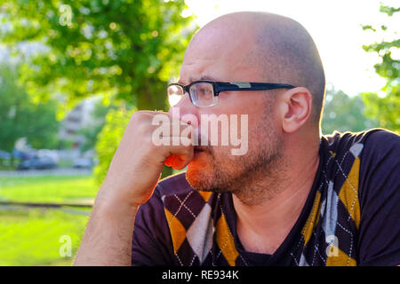 Der Mann mit der Brille leidet unter Depressionen. Probleme im persönlichen Leben und bei der Arbeit. Stress und Depressionen. Migräne ist eine Folge von Stress. Stockfoto