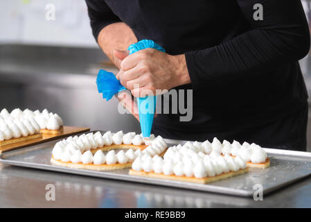 Nahaufnahme, Hände der Chef mit Süßwaren Beutel creme Vorbereitung einer fiftie Jahre alt Geburtstag Kuchen in der Konditorei Küche. Stockfoto