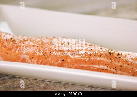 Closeup raw gespickt, Lachs in Rechteck pot. Roher Lachs mit Pfeffer. Stockfoto