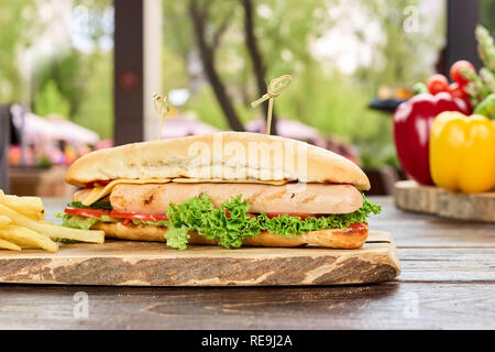 Hot Dog mit Hühnchen Würstchen und Pommes Frites. Closeup lecker Hot Dog auf Holzbrett. Stockfoto