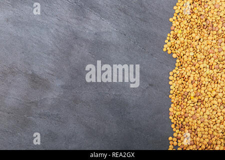Roh Linsen auf Schwarz Stein Hintergrund. Gesunde vegetarische Essen Konzept. Superfoods. Ansicht von oben, kopieren. Linsen sind reich an komplexen Kohlenhydraten, f Stockfoto