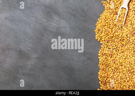 Roh Linsen auf Schwarz Stein Hintergrund. Gesunde vegetarische Essen Konzept. Superfoods. Ansicht von oben, kopieren. Linsen sind reich an komplexen Kohlenhydraten, f Stockfoto