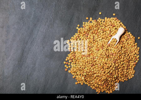 Roh Linsen auf Schwarz Stein Hintergrund. Gesunde vegetarische Essen Konzept. Superfoods. Ansicht von oben, kopieren. Linsen sind reich an komplexen Kohlenhydraten, f Stockfoto
