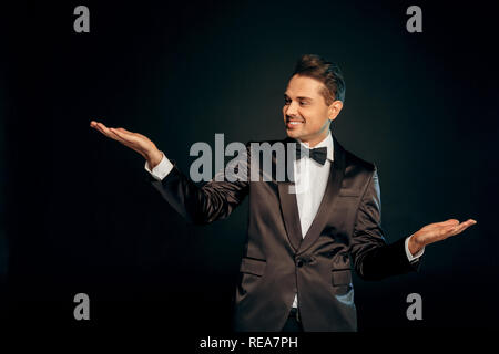 Berufliche Tätigkeit. Showman in der Klage stehen auf Schwarz, Raum isoliert neben freudigen Stockfoto