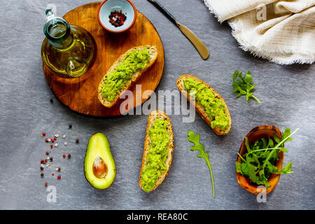 Avocado Toasts mit Rucola flach. Gute Fette raw Gesunde Ernährung Konzept. Stockfoto