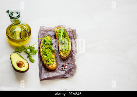 Frische avocado Toasts mit Rucola hautnah. Gute Fette raw Gesunde Ernährung Konzept. Stockfoto