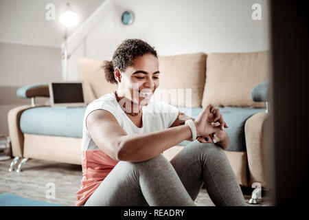 Fröhliche junge Dame lachen und über Bildschirm auf Ihre Uhr Stockfoto