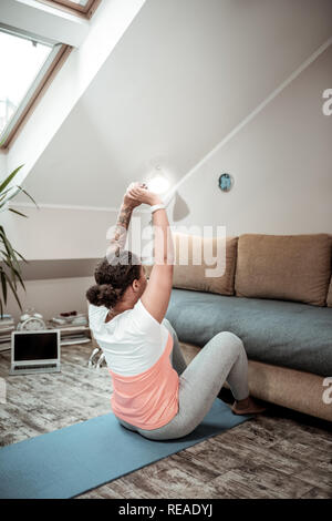 Friedliche curly behaarte Frau schwingen drücken Sie auf Blue mat Stockfoto