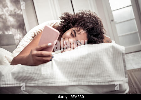 Curly fröhliche Frau, die mit dem Schlaf zufrieden Stockfoto