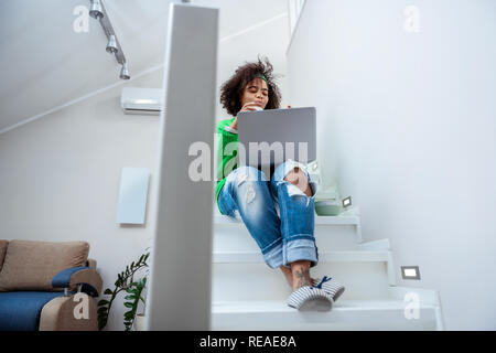 Modische Frau mit grünen Pullover und gemütliche Hausschuhe Zufrieden Stockfoto