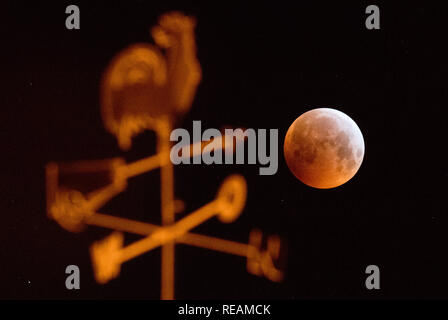 Laatzen, Deutschland. Jan, 2019 21. Verdunkelt, der Vollmond erscheint als so genannte 'Blood Moon' und erscheint rötlich - hinter einem Wetterhahn auf dem Dach eines Hauses fotografiert. Mond, Sonne und Erde sind genau in einer Linie während einer Mondfinsternis. Credit: Julian Stratenschulte/dpa/Alamy Leben Nachrichten Quelle: dpa Picture alliance/Alamy leben Nachrichten Stockfoto