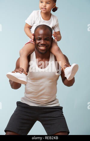 Stattlichen schwarzen Jungen Vater tut hockt mit seinem süßen kleinen Tochter ihn reiten. Sie haben Spaß, Lachen zusammen. Stockfoto