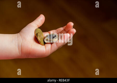 Kind Euro Münze in der Hand. Taschengeld stock Bild. Armen niedrigen Einkommensgruppe. Der dunkle Hintergrund. - Bild. Nahaufnahme Stockfoto