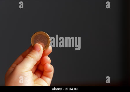 Kind Euro Münze in der Hand. Taschengeld stock Bild. Armen niedrigen Einkommensgruppe. Der dunkle Hintergrund. - Bild. Nahaufnahme Stockfoto