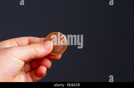 Kind Euro Münze in der Hand. Taschengeld stock Bild. Armen niedrigen Einkommensgruppe. Der dunkle Hintergrund. - Bild. Nahaufnahme Stockfoto