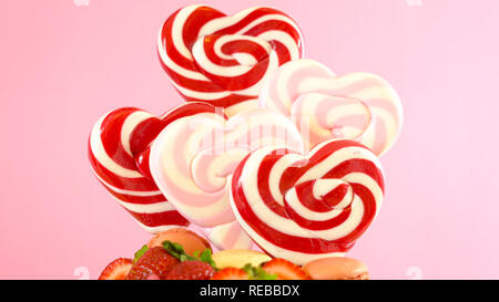 Valentinstag auf - Tendenz candyland Fantasy drip Neuheit Kuchen mit herzförmige Lollis, Candy und frische Erdbeeren dekoriert. Stockfoto