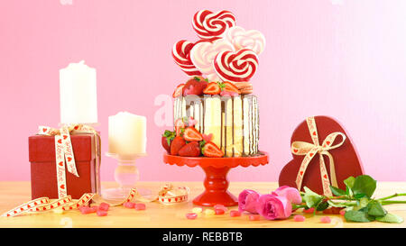 Valentinstag auf - Tendenz candyland Fantasy drip Neuheit Kuchen mit herzförmige Lollis, Candy und frische Erdbeeren dekoriert. Stockfoto