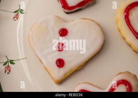 Valentinstag Cookies im Herzen Formen in Weiß mit rotem Rahmen und Design gefrostet. Stockfoto