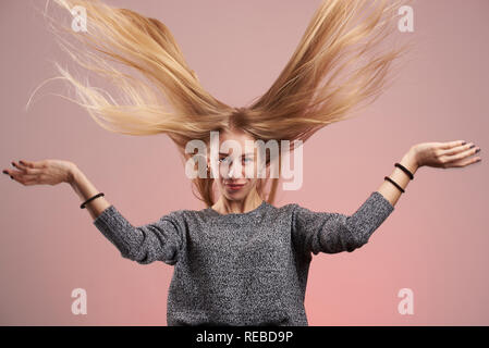 Junge blonde Mädchen mit langen Haare fliegen Um auf rosa Hintergrund isoliert Stockfoto