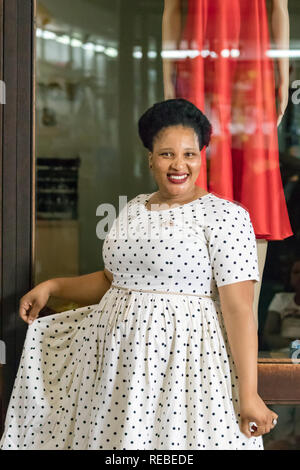 Durban, Südafrika - Januar 07th, 2019: eine schwarze afrikanische Frau, Modedesigner, posing trägt ein Kleid mit Punkten vor ihr speichern. Stockfoto