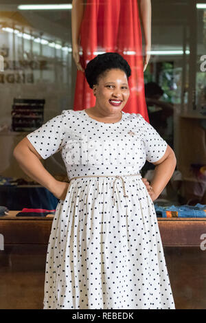 Durban, Südafrika - Januar 07th, 2019: eine schwarze afrikanische Frau, Modedesigner, posing trägt ein Kleid mit Punkten vor ihr speichern. Stockfoto