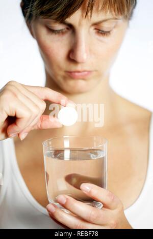 Junge Frau Auflösen eines Tablet-PC in einem Glas Wasser Stockfoto