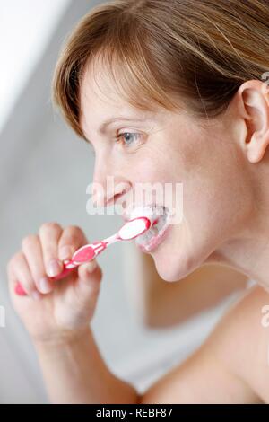 Junge Frau im Badezimmer die Zähne putzen Stockfoto