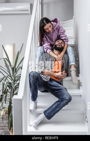 Stilvolle Paar sitzt auf der Treppe, während zu Hause ausruhen Stockfoto