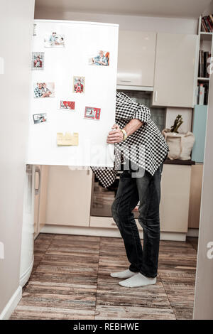 Mann in Jeans und Shirt Öffnen der Tür der Kühlschrank Stockfoto