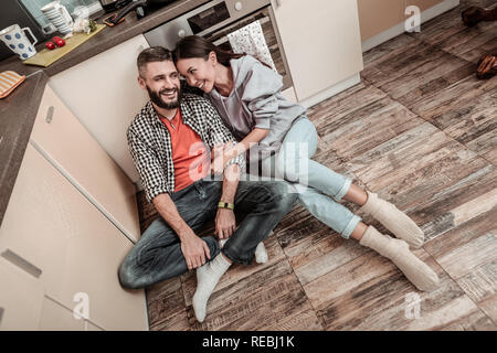 Gut aussehender bärtiger Mann Gefühl glücklich in der Nähe von seiner Freundin sitzen Stockfoto